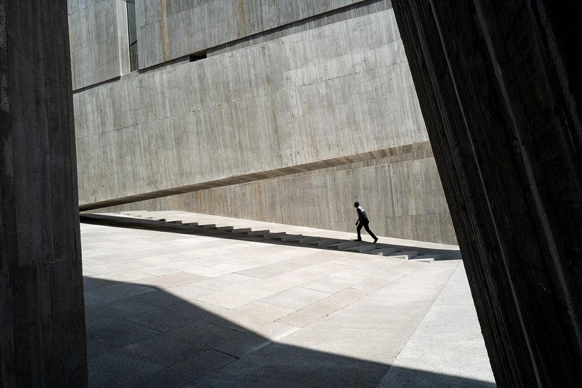 A person walking through a large architectural space in black and white