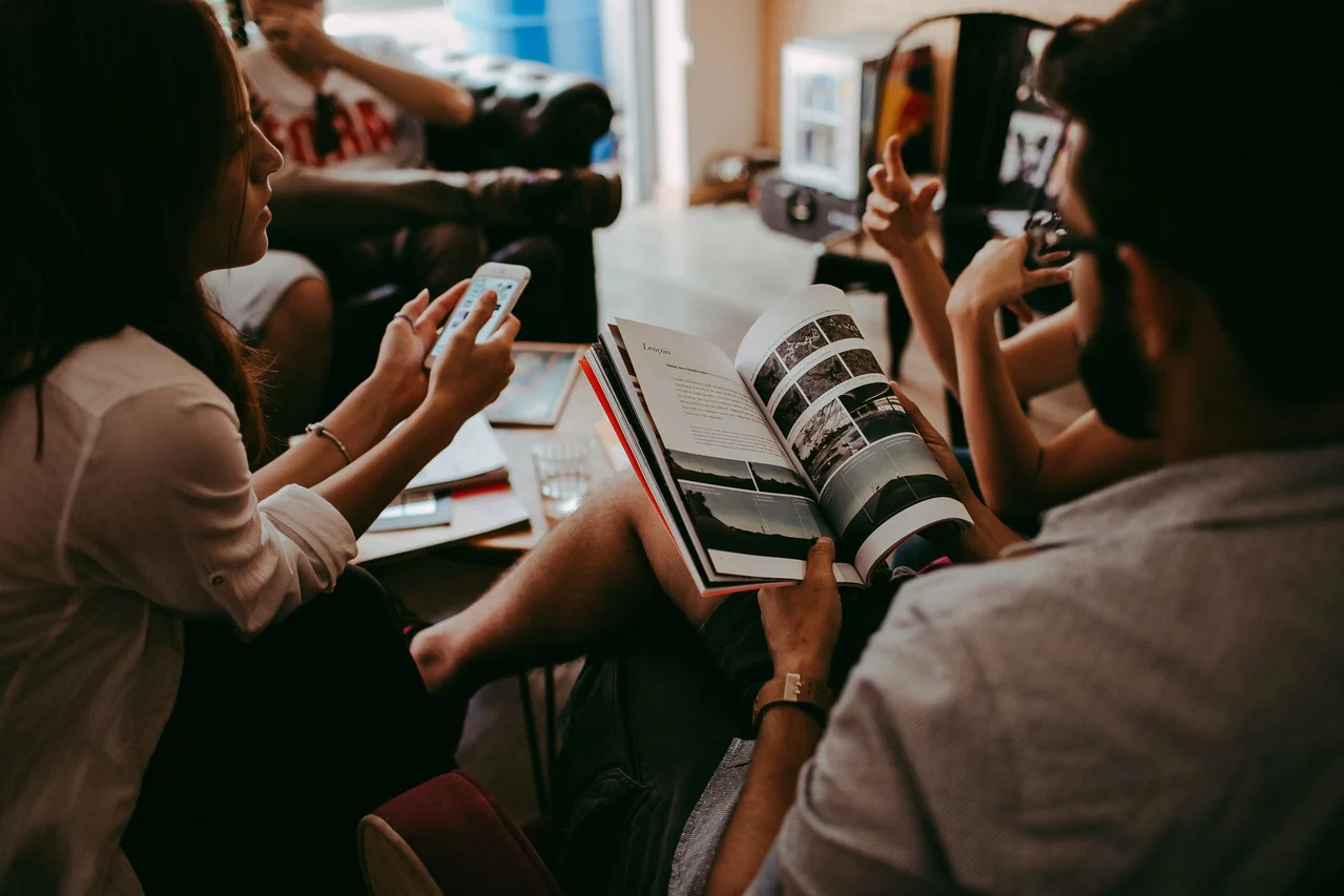A small group reading a magazine and talking together indoors
