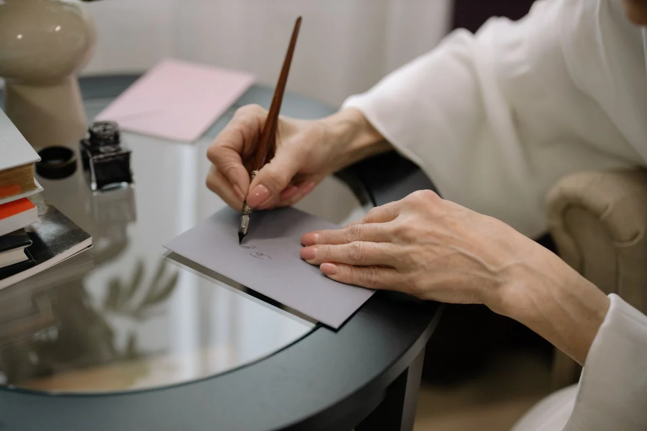 Hands carefully writing on an envelope with a fountain pen